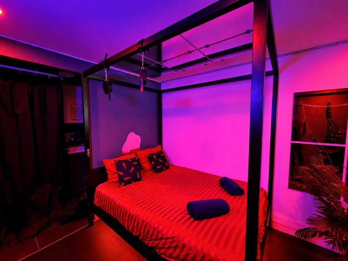 Lit sous lumière rouge et violette, dans la Suite Éros à Souppes-sur-Loing