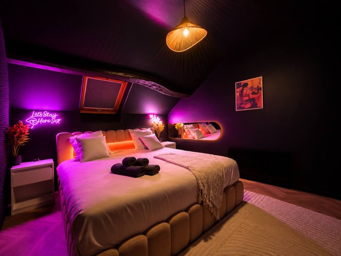 Chambre sous les toits en lumière violette, dans la Suite Pothos à Souppes-sur-Loing